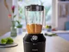 A black Philips blender with a glass pitcher filled with an orange liquid is placed on a kitchen counter. Náhľad obrázku produktu