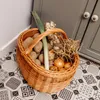 A wicker basket filled with fresh vegetables sits on a patterned floor next to a gray cabinet. Produktbild-Vorschau