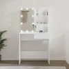 A white vanity table with a lighted mirror and shelves, set against a white wall with a plant to the left. Voir les images du produit