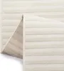 A close-up view of a folded rug, showing its texture and striped pattern. The underside of the rug is also visible. Voir les images du produit