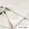 A close-up view of a cream-colored fabric with neat edges, possibly a curtain or tablecloth, with a sprig of greenery in the upper left corner. Produktbild-Vorschau