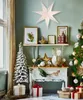 A festive Christmas scene with a decorated tree, gifts, and a large paper star hanging above a shelf. Produktbild-Vorschau