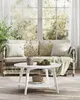 A living room scene with a sofa and a coffee table in front of a large window. Produktbild-Vorschau