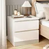 A bedside table with decorative items and a lamp next to a bed. Produktbild-Vorschau