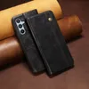 A black leather phone case is shown lying on a brown leather surface, with rolls of tan and brown leather in the background. Produktbild-Vorschau