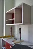 A cabinet is being supported by two adjustable stands on a workbench, with tools nearby. Anteprima dell’immagine prodotto