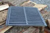 A cast iron grate rests on a pile of firewood. Anteprima dell’immagine prodotto