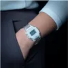 A close-up shot of a person's wrist wearing a clear digital watch, with their hand in the pocket of dark gray pants. Produktbild-Vorschau
