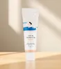 A tube of sunscreen is placed on a wooden surface with a light gray background and shadows. Náhled obrázku produktu