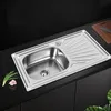 A stainless steel kitchen sink with a draining board is shown on a black countertop. Produktbild-Vorschau