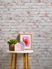 A small side table with decorative items against a brick wall. Produktbild-Vorschau