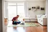 A father and baby are playing on a mat in a living room. Produktbild-Vorschau