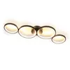 A modern, black ceiling lamp with four interconnected rings, illuminated from within, is presented against a white background. Voir les images du produit