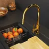 A modern kitchen sink area with a gold faucet and oranges in a drying rack. Podgląd zdjęcia produktu