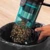 A hand is emptying a vacuum cleaner's dustbin into a trash bag. Produktbild-Vorschau