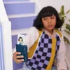 A young person is sitting on stairs holding a Canon Zoemini S2 aquamarine instant camera and a printed photo. Anteprima dell’immagine prodotto