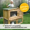 A young boy gives a thumbs up next to a wooden rabbit hutch in a garden. Produktbild-Vorschau