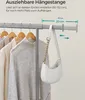 A close-up of an extendable clothes rail with clothes hanging on it and a handbag hanging from the rail. Produktbild-Vorschau