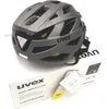 A grey Uvex bicycle helmet is displayed on a white surface next to its packaging and tags. Produktbild-Vorschau