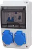 A white electrical distribution box with a transparent cover, showing circuit breakers inside, and two blue electrical outlets on the front. Produktbild-Vorschau