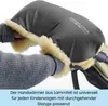 A person's hands are inserted into a gray stroller hand warmer lined with cream-colored sheepskin. Produktbild-Vorschau