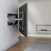 A TV wall mount attached to a wall, with a TV attached to the mount. Produktbild-Vorschau