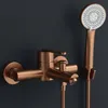A copper-colored bathtub faucet with a handheld showerhead mounted on a dark gray wall. Náhľad obrázku produktu