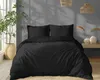 A bedroom scene with a bed dressed in black bedding, a plant in a pot, and decorative items on a shelf. Produktbild-Vorschau