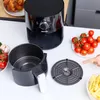 An air fryer and its accessories are laid out on a white table, with some ingredients and a plate of french fries. Produktbild-Vorschau