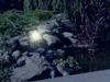 A solar-powered garden light illuminates a rock garden with a pond at night. Anteprima dell’immagine prodotto