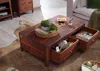 A wooden coffee table with drawers open, displaying magazines and knitting supplies, placed on a rug in a living room setting. Produktbild-Vorschau