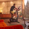 A man is exercising on an Adidas exercise bike in a modern living room. Produktbild-Vorschau