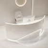 A modern, white reception desk with a curved design and integrated lighting, along with a computer monitor and a chair. Produktbild-Vorschau
