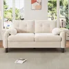 A beige sofa is shown in a well-lit room with large windows in the background. Náhľad obrázku produktu