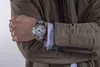 A close-up shot of a person's arm wearing a silver watch and a brown jacket. Náhled obrázku produktu