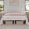 A white metal bed frame with a diamond pattern on the headboard and footboard, set up in a bedroom with bedding. Podgląd zdjęcia produktu