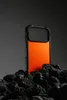 A phone case is displayed on a pile of dark rocks against a dark gray background. Podgląd zdjęcia produktu