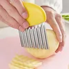 A person is using a wavy-edged cutter to slice a potato on a pink cutting board. Podgląd zdjęcia produktu