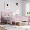 A pink metal bed frame with a cloud pattern headboard, set up in a bedroom with a framed picture on the wall and a window with blinds. Produktbild-Vorschau