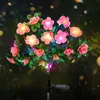 A solar-powered string of lights shaped like pink flowers with green leaves, illuminated at night with bokeh lights in the background. Náhled obrázku produktu