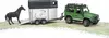 A toy green Land Rover Defender towing a horse trailer with a black horse standing on the ramp. Produktbild-Vorschau