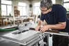 A man is using a table saw in a workshop. Podgląd zdjęcia produktu