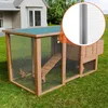 A wooden chicken coop with a green roof sits on a grassy lawn in front of a house. A roll of wire mesh is shown in an inset circle. Produktbild-Vorschau