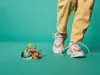 A person's legs and feet wearing sneakers stand over a small LEGO Minecraft set on a teal background. Podgląd zdjęcia produktu