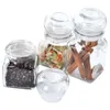 Four glass jars containing spices and cinnamon sticks, arranged on a white background. Voir les images du produit
