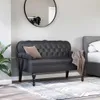 A dark gray tufted bench with a brown pillow and a draped blanket sits in a room next to a bed. Náhled obrázku produktu