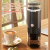 A portable electric espresso machine sits on a wooden table next to a cup of coffee, with text overlays describing its features. Náhled obrázku produktu