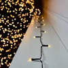 A string of warm white LED lights is laid out on a white surface, with a blurred background of more warm white lights. Podgląd zdjęcia produktu