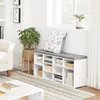 A shoe cabinet with a padded seat is placed next to a window, with decorative items and plants in the room. Náhľad obrázku produktu