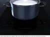 A pot of liquid is being heated on a black induction cooktop with digital controls. Produktbild-Vorschau